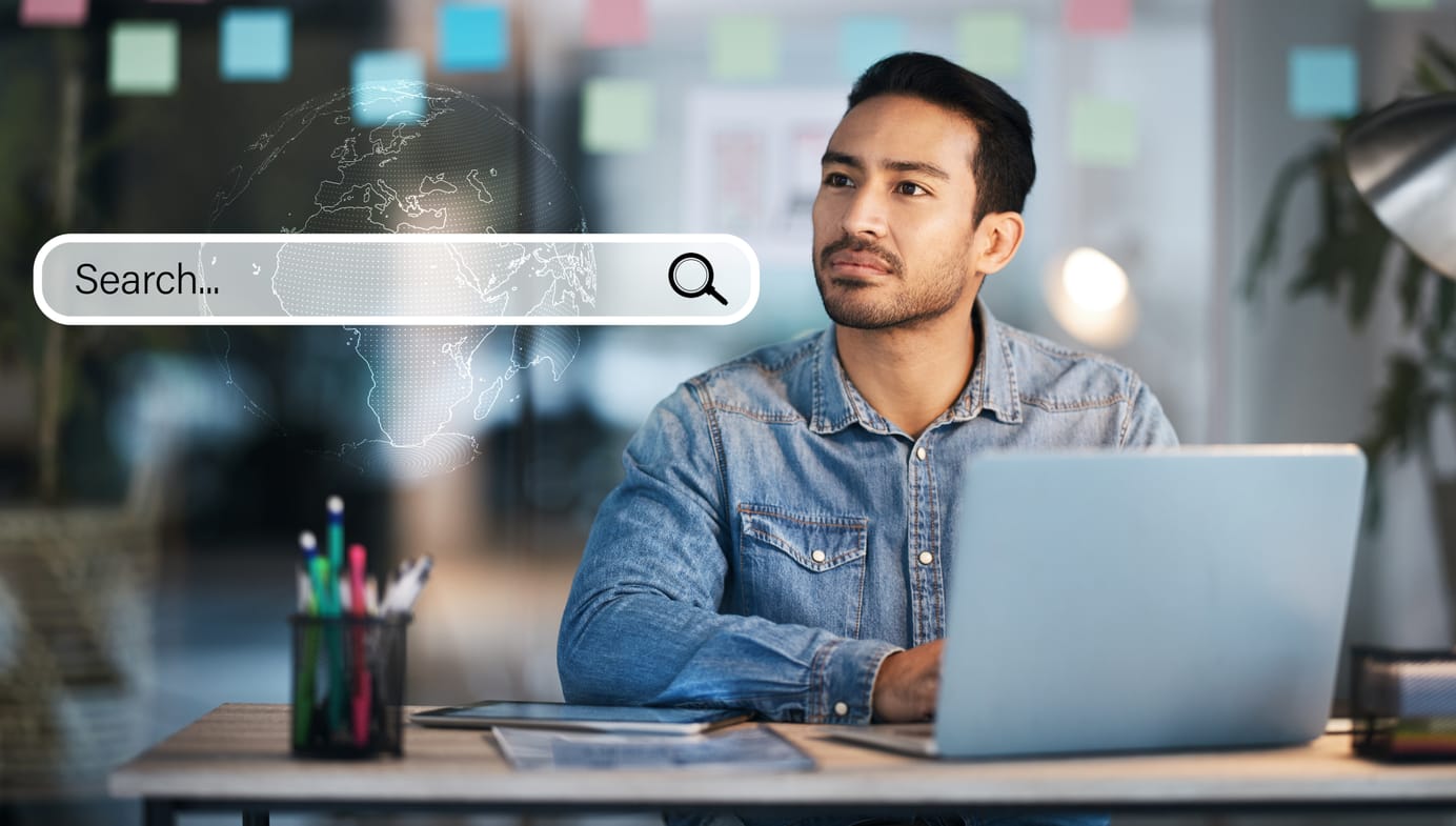 Man at laptop with a search bar overlay, symbolizing user intent and E-E-A-T for improved online visibility.